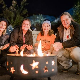 Group sitting by a fire pit in the evening at Eden